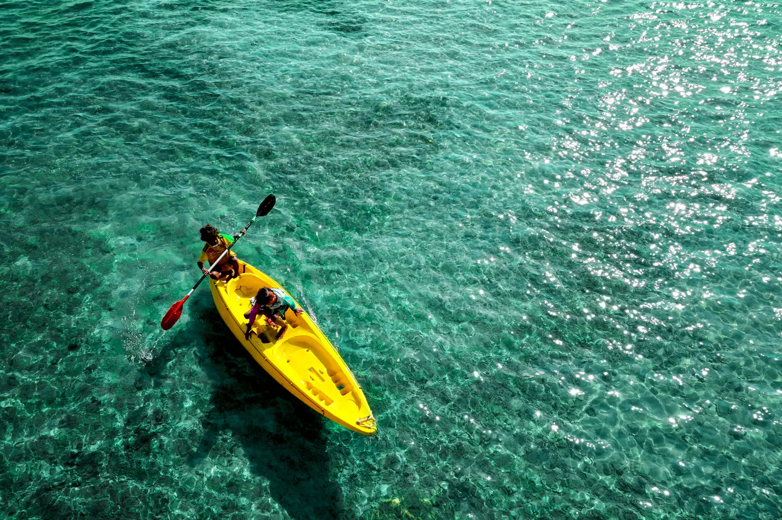 Kayaking on clear green water. Photo by Maxim Mox on Unsplash